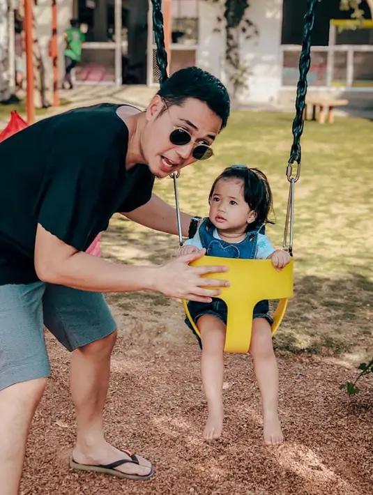 Meski hanya menemani sang putri bermain ayunan, nyatanya Kinos juga tampil simpel sekaligus trendi. Ia mengenakan kaus dan celana pendek tapi juga memakai kacamata hitam. Lembar tampak antusias saat berada di ayunan tersebut dengan menatap sang ayah terus menerus. (Liputan6.com/IG/@kinosnoski)