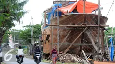 Warga melintas di area pembuatan perahu di Balongan, Indramayu, Jawa Barat, Jumat (15/1/2016). Dibutuhkan waktu selama delapan bulan untuk menyelesaikan satu unit perahu yang dijual seharga Rp.4 miliar - Rp.5 miliar tersebut. (Liputan6.com/Helmi Afandi)