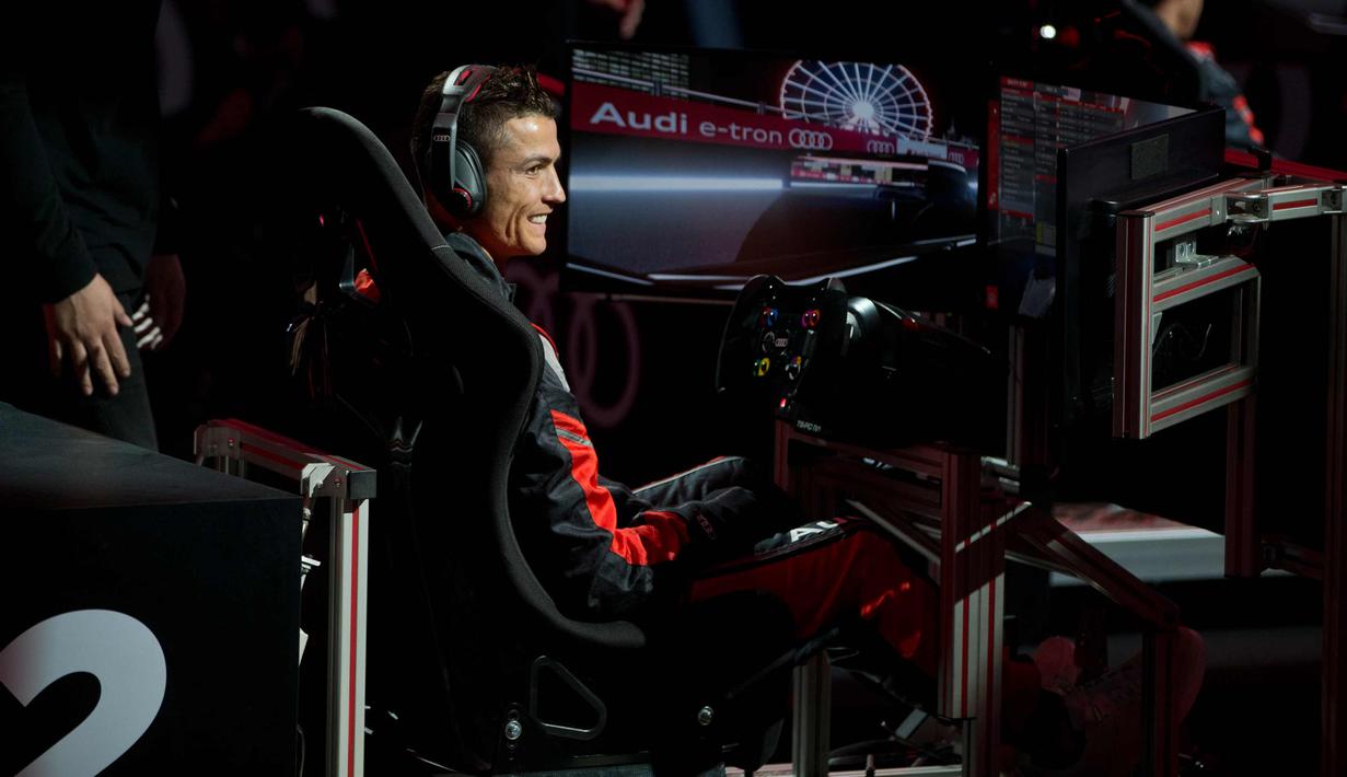 Penyerang Real Madrid, Cristiano Ronaldo tersenyum pada akhir balapan di simulator Formula E selama sebuah acara promosi di Madrid, Spanyol, (23/11). (AP Photo / Paul White)