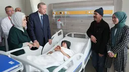 Gambar selebaran yang dirilis pada 22 Februari 2023 menunjukkan Presiden Turki Recep Tayyip Erdogan (kiri ke-2) dan istrinya Emine Erdogan (kiri) mengunjungi anak korban gempa yang menerima perawatan di Fakultas Kedokteran Universitas Ankara setelah dipindahkan dari daerah yang dilanda gempa di Turki. Presiden Erdogan menjanjikan akan menghidupkan kembali daerah terdampak gempa Turki dalam jangka waktu setahun. (Press Office of the Presidency of Turkey / AFP)