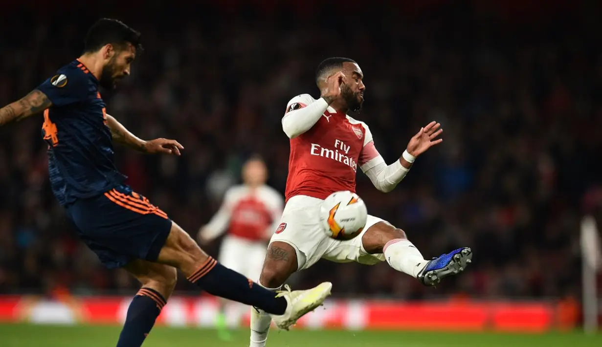 Lacazette menghentikan tendangan pemain Valencia pada leg 1, semifinal Liga Europa yang berlangsung di Stadion Emirates, London, Jumat (3/5). Arsenal menang 3-1 atas Valencia. (AFP/Glyn Kirk)