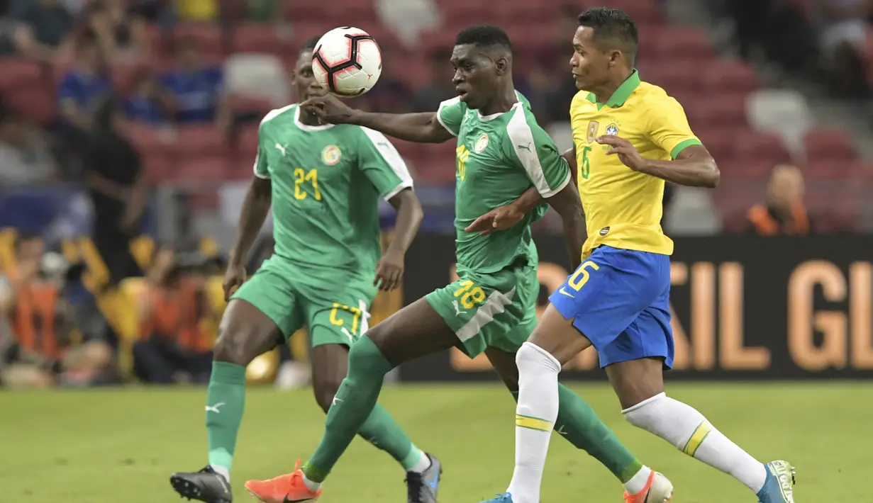 Pemain Senegal Ismaila Sarr (tengah) berebut bola dengan bek Brasil bertarung pada pertandingan persahabatan di Stadion Nasional di Singapura (10/10/2019). Brasil bermain imbang dengan Senegal 1-1. (AFP Photo/Roslan Rahman)