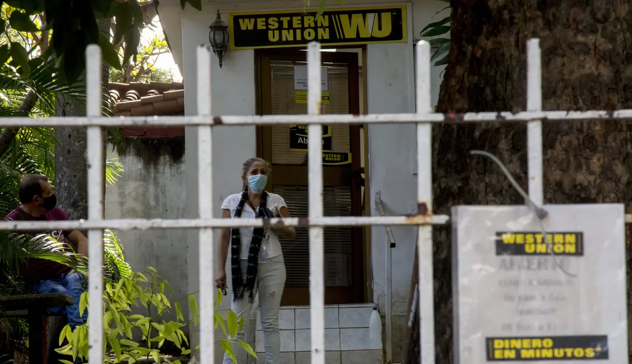 Seorang perempuan menunggu di luar kantor Western Union sebelum penutup kantor di Havana, Kuba, Senin (23/11/2020). Penutupan yang didorong oleh sanksi keras AS itu akan membuat ribuan warga Kuba yang biasa menggunakan jasa perusahaan pengiriman uang tersebut kehilangan akses. (AP/Ismael Francisco)