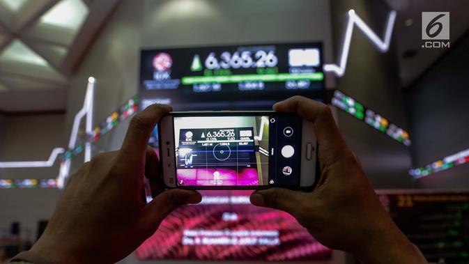 Pengunjung mengambil foto layar indeks harga saham gabungan yang menunjukkan data di Bursa Efek Indonesia, Jakarta, Selasa (2/1).(Liputan6.com/Faizal Fanani)
