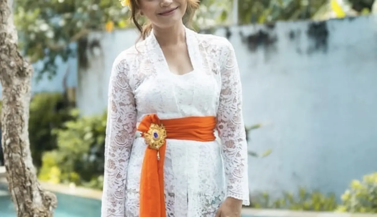 Ibu satu anak ini pun tampil mengenakan kebaya kutu baru putih dipadu obi orange khas perempuan Bali. Dengan bawahan kain lilitnya. (@itsrossa910)