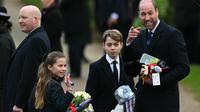 Pangeran William, Pangeran George (tengah), dan Putri Charlotte memegang hadiah dari para simpatisan setelah menghadiri kebaktian Natal Kerajaan Inggris di Gereja St Mary Magdalene, Sandringham, Norfolk, Inggris timur, 25 Desember 2024. (Oli SCARFF/AFP)