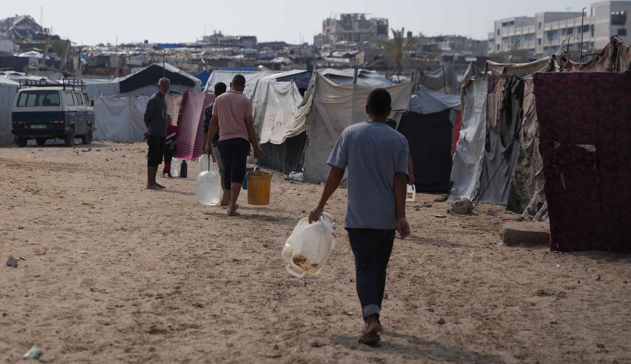 Warga hanya mendapatkan 6 hingga 7 liter air per hari, jauh di bawah standar kemanusiaan. Tampak dalam foto, para pengungsi Palestina membawa jerigen berisi air melalui kamp tenda di Khan Younis, Jalur Gaza Selatan, Kamis 30 April 2026. (AP Photo/Abdel Kareem Hana)