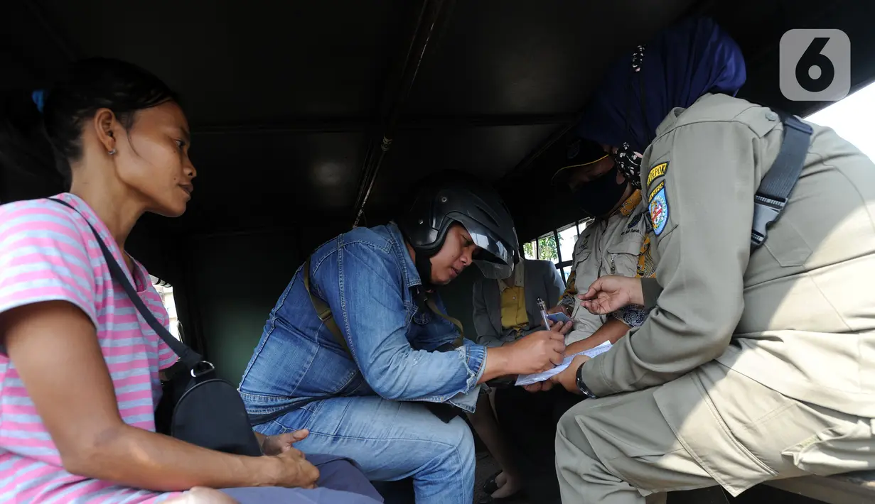 Petugas melakukan denda terhadap warga yang tidak mengenakan masker di kawasan Jalan Ir. H. Juanda, Depok, Jawa Barat, Kamis (23/7/2020). Sejumlah pengendara dan penumpang angkutan umum terjaring razia Gugus Tugas Percepatan Penanganan COVID-19 Kota Depok. (merdeka.com/Arie Basuki)