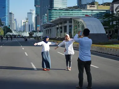 Dua orang wanita berfoto dengan latar belakang Jalan MH Thamrin yang masih ditutup oleh aparat keamanan di Jakarta, Jumat (24/5/2019). Ditutupnya Jalan MH Thamrin terkait unjuk rasa menolak hasil Pemilu 2019 dimanfaatkan sebagian warga untuk berfoto. (Liputan6.com/Immanuel Antonius)