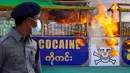 Seorang perwira polisi mengamati narkotika sitaan yang dibakar dalam acara pemusnahan pada Hari Antinarkoba Sedunia, di Yangon, Senin (26/6). Myanmar membakar opium, heroin, dan kokain senilai sekitar US$385 juta, setara Rp5,1 miliar. (AP Photo/Thein Zaw)