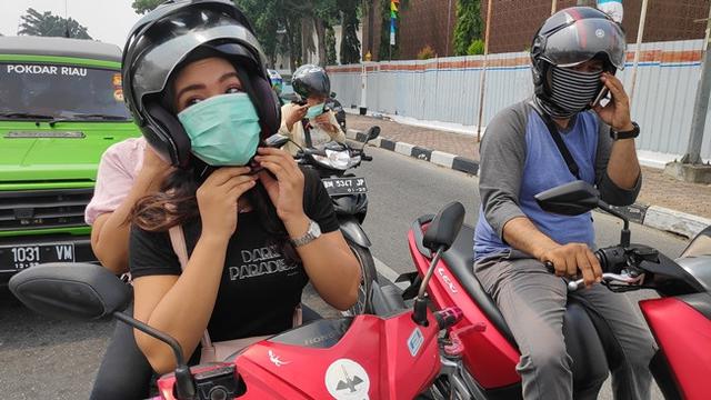 Warga mulai memakai masker agar tidak menghirup kabut asap yang menyelimuti Pekanbaru.