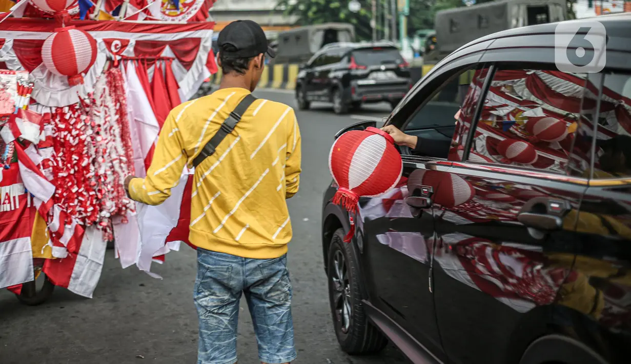 Seorang pedagang bendera merapikan umbul-umbul dan bendera yang di jual di Sepanjang Jalan Jatinegara, Jakarta, Selasa (2/8/2022). Jelang peringatan HUT Kemerdekaan RI ke-77, pedagang musiman bendera  mulai bermunculan mereka memanfaatkan trotoar untuk memajang dagangannya, mulai dari umbul-umbul, bendera, hingga ornamen khas merah putih lainnya dengan harga yang tawarkan juga bervariasi, mulai dari Rp. 5.000 ,- hingga Rp. 300.000,. (Liputan6.com/Faizal Fanani)