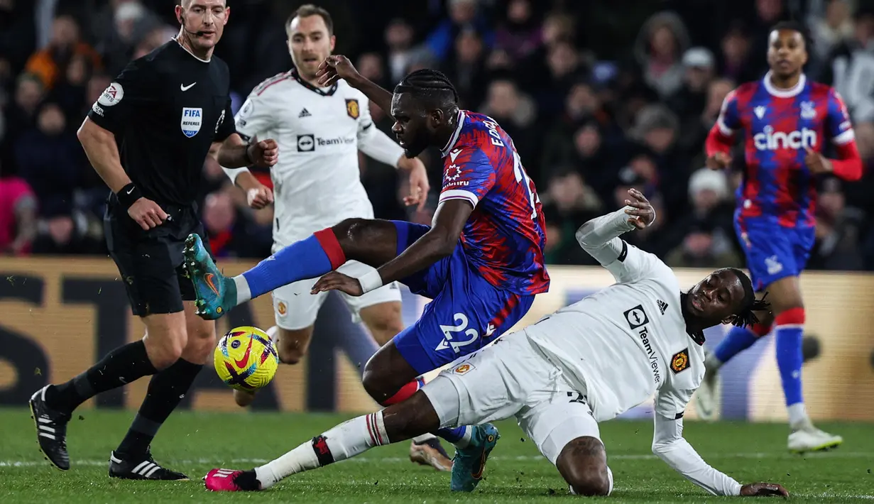 Striker Crystal Palace Odsonne Edouard (Tengah) dijegal oleh bek Inggris Manchester United (MU) Aaron Wan-Bissaka saat berebut bola pada matchday 19 Liga Inggris di Stadion Selhurst Park, London, Kamis dini hari WIB (19/1/2023). Duel Crystal Palace lawan MU berlangsung ketat sejak awal babak pertama. (ADRIAN DENNIS / AFP)