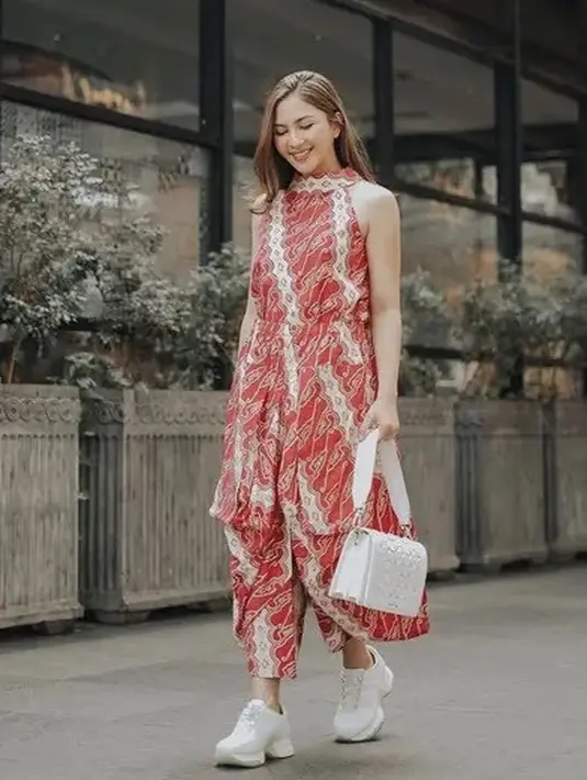 Jessica Mila memilih mengenakan jumpsuit warna merah dengan motif batik. Tampil kasual dengan tas dan sneakers putihnya. [@jscmila]
