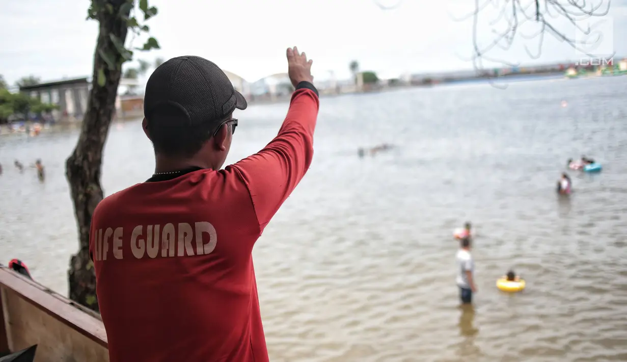 Penjaga pantai berjaga di Beach Pool Ancol, Jakarta, Selasa (25/12). Pasangnya air laut dan cuaca buruk mengakibatkan pantai Ancol sepi pengunjung saat libur Natal 2018. (Liputan6.com/Faizal Fanani)
