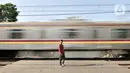 Penjaga perlintasan berdiri saat kereta melintas di Jalan Duri Kosambi Raya, Jakarta, Rabu (15/1/2020). Warga setempat membangun palang secara swadaya dan mengatur lalu lintas karena belum dipasangnya palang pintu otomatis perlintasan kereta dekat Stasiun Rawa Buaya itu. (merdeka.com/Iqbal Nugroho)