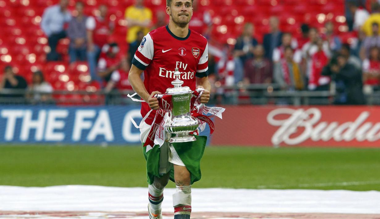 Aaron Ramsey berlari sambil membawa trofi Piala FA saat merayakan kemenangan Arsenal usai menumbangkan Hull City 3-2 di final di Stadion Wembley, London, (18/5/2014). (REUTERS/Eddie Keogh)