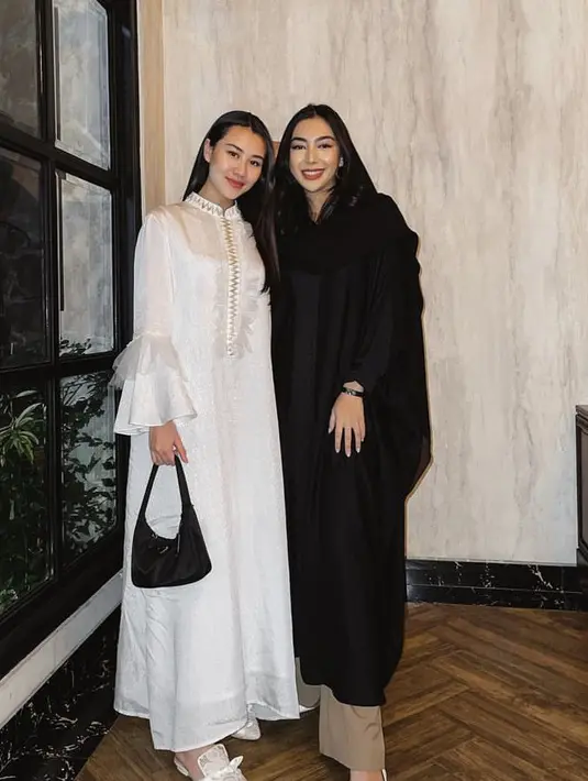 Ia juga memilih mengenakan gamis putih dengan aksen keemasan dibagian dada lalu lengan model terompet berlace. Dipadukan sandal selop putih sambil membawa handbag hitam [@aaliyah.massaid]