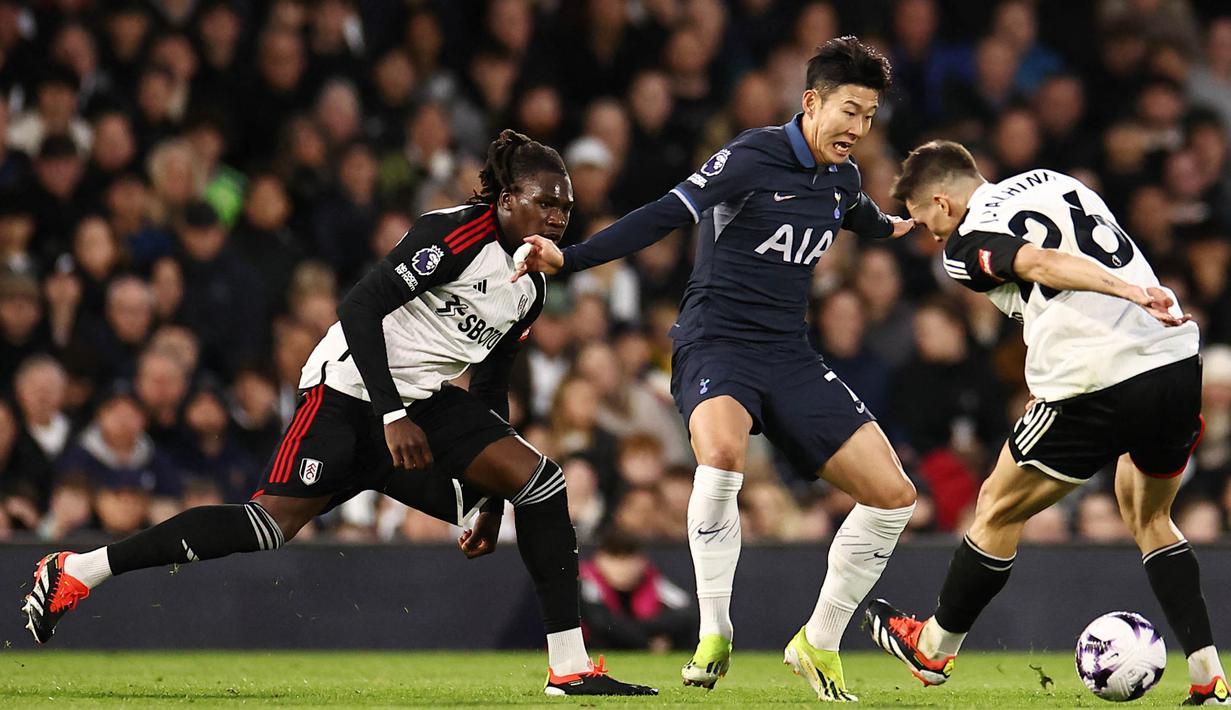 Pemain Tottenham Hotspur, Son Heung-Min, berusaha melewati pemain Fulham pada laga Liga Inggris di Stadion Craven Cottage, Minggu (17/3/2024). Kekalahan ini membuat Spurs membuang kesempatan untuk menembus empat besar klasemen. (AFP/Henry Nicholis)