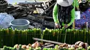 Seorang peserta bersiap memasak lemang, hidangan nasi ketan tradisional yang dimasukkan ke dalam tabung bambu dan diisi dengan santan yang kemudian diletakkan di atas api, selama acara memasak massal di Blang Pidie, Kabupaten Aceh Barat Daya, Aceh, pada Sabtu 25 April 2026. (CHAIDEER MAHYUDDIN/AFP)
