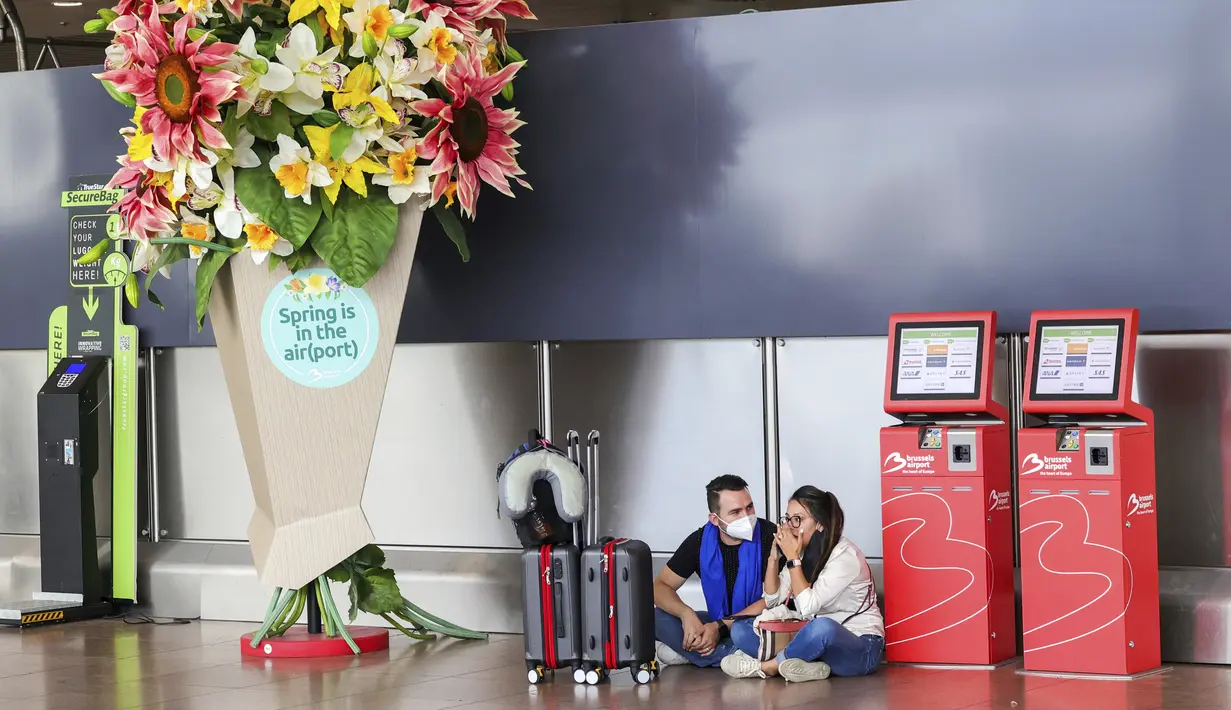 Pasangan menunggu dengan barang bawaan mereka di ruang keberangkatan bandara internasional Brussels selama pemogokan nasional di Brussels, Belgia, Senin (20/6/2022). Serikat pekerja mengatakan 80.000 orang mengambil bagian dalam pemogokan nasional Senin, yang mengganggu rute transportasi di ibu kota Belgia sepanjang hari. (AP Photo/Olivier Matthys)