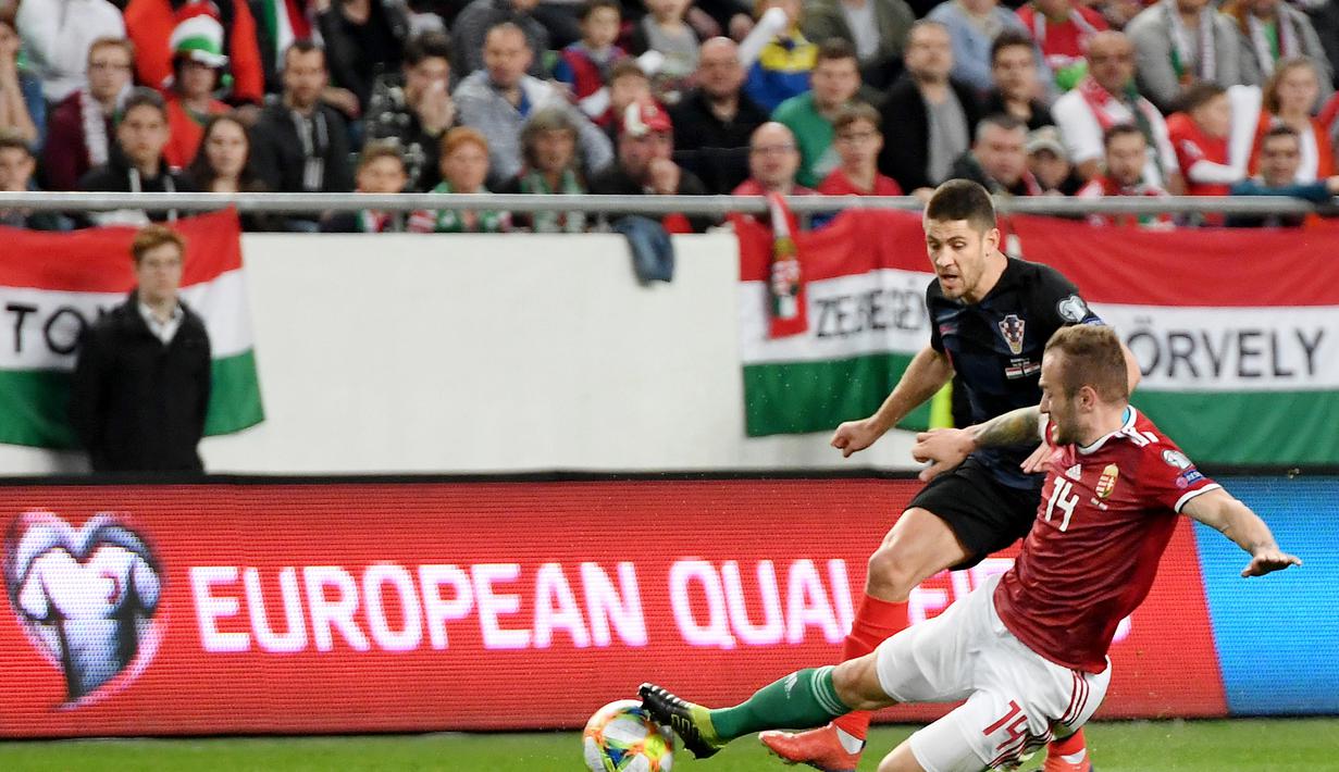 Aksi Ante Rebic dihadang bek Hungaria, Gergo Lovrencsics pada laga kedua babak kualifikasi Piala Eropa 2020 Grup E yang berlangsung di Stadion Groupama Arena, Budapest, Senin (25/3). Kroasia kalah 1-2 kontra Hungaria. (AFP/Attila Kisbenedek)