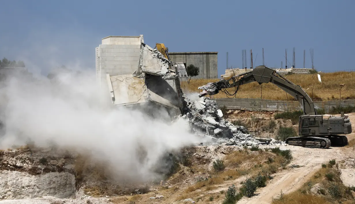 Alat berat Israel menghancurkan salah satu bangunan Palestina di desa Palestina Sur Baher di Yerusalem Timur (22/7/2019). Palestina menuduh Israel menggunakan keamanan sebagai dalih untuk mengusir mereka dari Tepi Barat. (AFP Photo/Ahmad Gharabli)