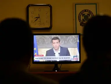 Wartawan menyaksikan pidato Perdana Menteri Yunani Alexis Tsipras di televisi di Athena, Kamis (20/8/2015). Dia mengumumkan pengunduran dirinya dan menyerukan pemilu dini tanggal 20 September. (AFP PHOTO/LOUISA GOULIAMAKI)