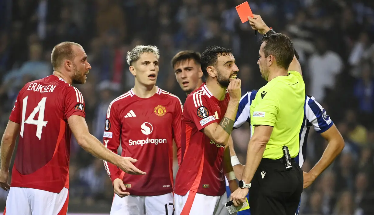 Pemain Manchester United, Bruno Fernandes, mendapat kartu merah setelah melakukan pelanggaran mengangkat kaki terlalu tinggi saat berduel dengan pemain FC Porto, Nehuen Perez, pada matchday 2 Liga Europa 2024/2025 di Estadio do Dragao, Jumat (4/10/2024). (AFP/Miguel Riopa)