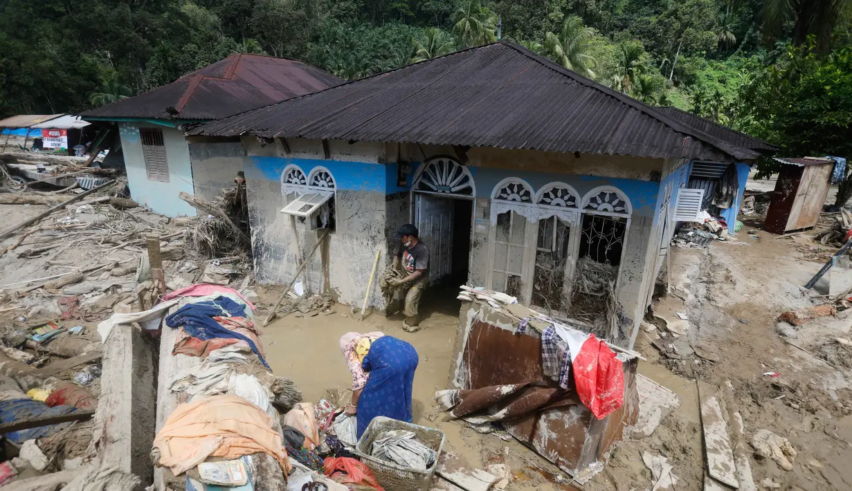 Selain korban jiwa, jumlah pengungsi juga terus meningkat. Tampak dalam foto, warga membersihkan rumah mereka dari lumpur di sebuah desa yang terdampak banjir bandang di Batang Toru, Sumatera Utara, Senin, 1 Desember 2025. (AP Photo/Binsar Bakkara)
