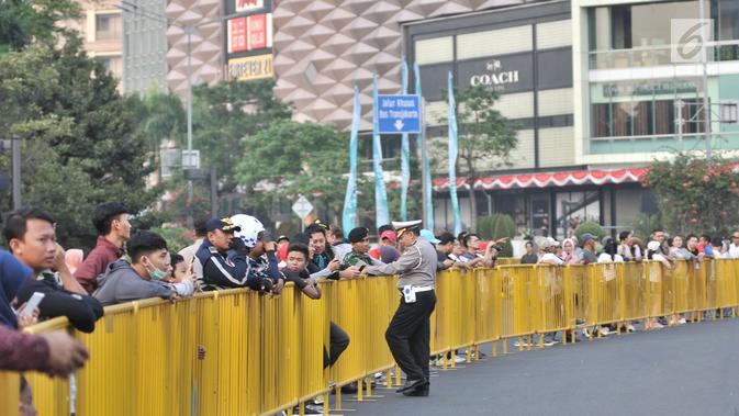 Warga berjejer dibalik pagar pembatas saat menunggu peserta lomba lari maraton Asian Games 2018 di kawasan MH Thamrin, Jakarta, Minggu (26/8). (Merdeka.com/Iqbal S. Nugroho)