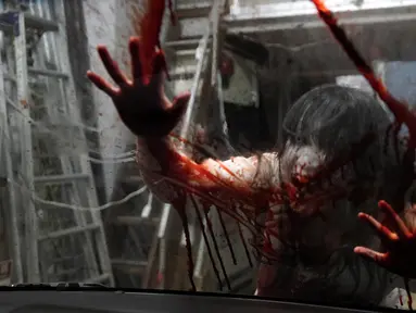 Pemeran zombie tampil dengan darah palsu yang disiramkan ke kaca kendaraan saat demonstrasi pertunjukan rumah hantu drive-in di Tokyo, Jepang, Selasa (18/8/2020). Rumah hantu drive-in ini diadakan di tengah pandemi COVID-19. (AP Photo/Eugene Hoshiko)