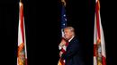 Capres AS dari Partai Republik, Donald Trump memeluk bendera AS saat melakukan kampanye menyapa pendukungnya di Tampa, Florida, AS (24/10). (REUTERS/Jonathan Ernst)