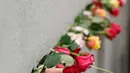 Orang-orang meletakkan bunga mawar di tembok selama peringatan runtuhnya Tembok Berlin, di bekas jalur perbatasan antara Berlin Timur dan Berlin Barat, di Bernauer Strasse, pada tanggal 9 November 2023. (Odd ANDERSEN/AFP)