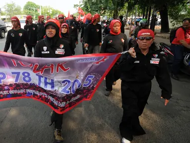 Beberapa buruh wanita membentangkan spanduk saat melakukan aksi jalan kaki menuju Tugu Proklamasi, Jakarta, Jumat (20/11/2015). Aksi ini bagian dari jalan kaki Bandung-Jakarta menolak PP 78 th 2015 tentang pengupahan. (Liputan6.com/Helmi Fithriansyah)