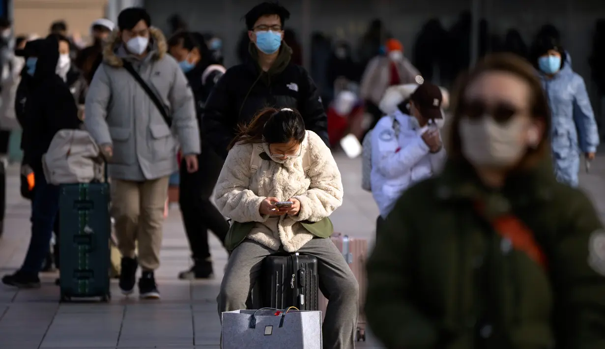 Seorang pemudik duduk di atas kopernya di luar pintu masuk Stasiun Kereta Api Beijing di Beijing, China, Sabtu (14/1/2023). Jutaan warga China diperkirakan akan melakukan perjalanan selama periode liburan Tahun Baru Imlek tahun ini. (AP Photo/Mark Schiefelbein)