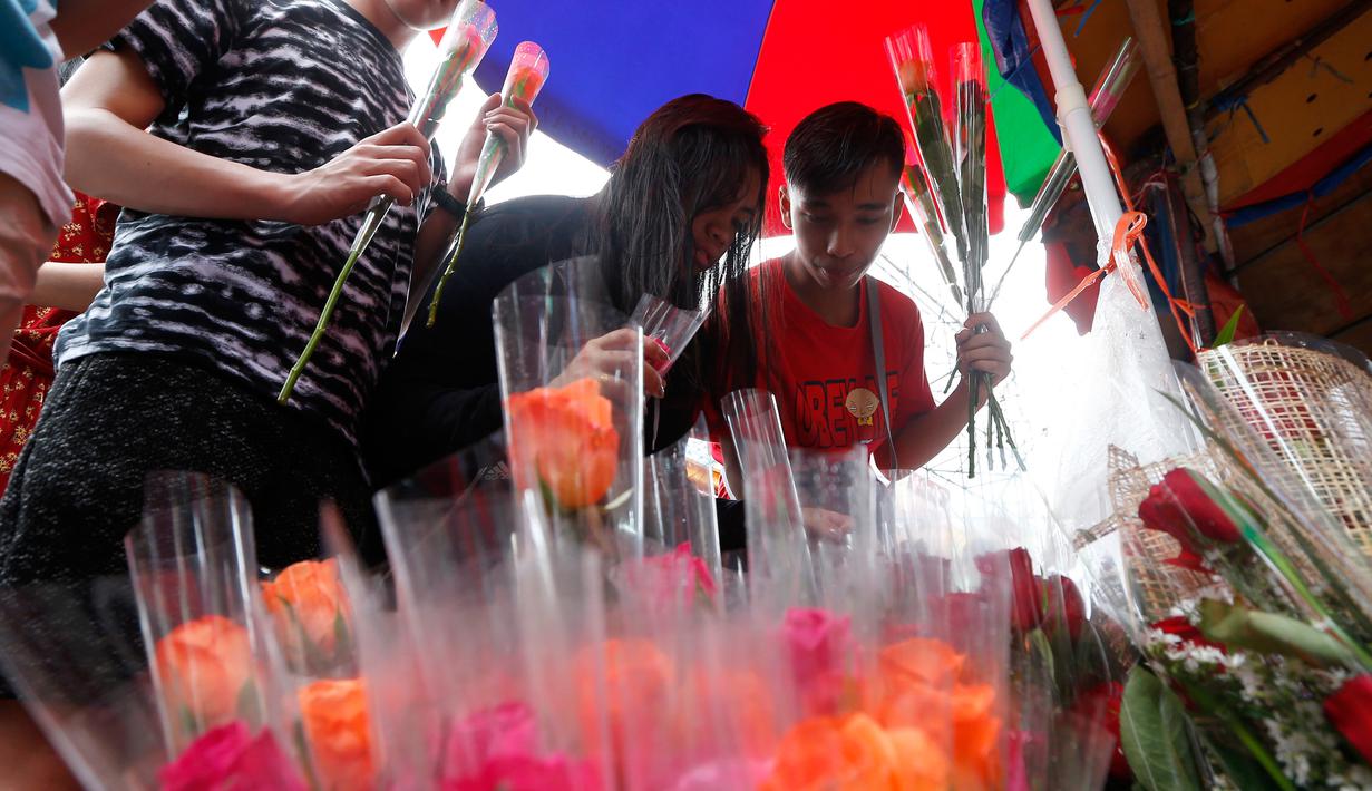 Orang-orang memilih bunga mawar yang dijajakan di sebuah pasar bunga sehari sebelum Valentine Day di Manila, Filipina, Rabu (13/2). Sudah tradisi di seluruh dunia, setiap hari valentine identik dengan pemberian bunga atau coklat. (AP Photo/Bullit Marquez)