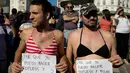 Dua pria mengenakan bikini memegang kertas bernada protes dalam unjuk rasa di Ibu Kota Argentina, Buenos Aires, Selasa (7/1). Mereka melakukan protes atas kekerasan yang dilakukan aparat kepolisian terhadap perempuan tanpa bra (AP Photo/Natacha Pisarenko)