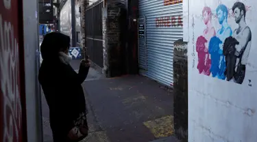 Seorang wanita mengambil gambar mural musisi asal Inggris, George Michael, di Shoreditch, London timur, 29 Desember 2016. Mural itu diciptakan seorang seniman jalanan Pegasus sebagai penghormatan terhadap mendiang George Michael. (REUTERS/Stefan Wermuth)