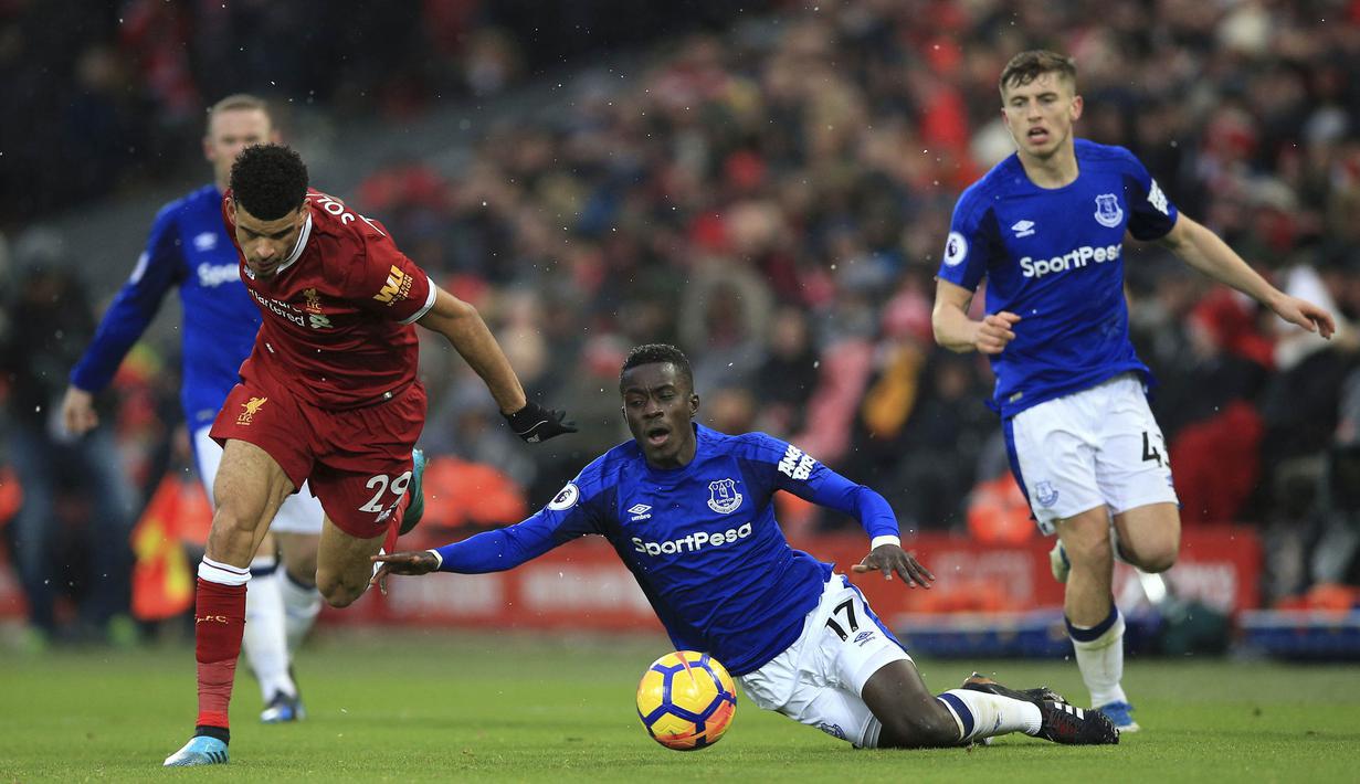 Gelandang Everton, Idrissa Gueye, terjatuh saat berusaha merebut bola dari striker Liverpool, Dominic Solanke, pada laga Premier League di Stadion Anfield, Minggu (10/12/2017). Laga bertajuk Derbi Merseyside itu berakhir imbang 1-1. (AP/Peter Byrne)