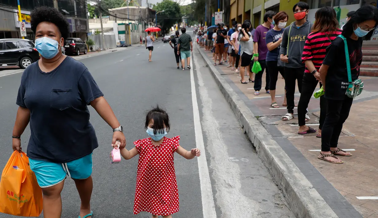 Pejalan kaki melintas dekat warga yang berdiri dengan jarak yang aman di garis antrean di luar supermarket di Manila, Filipina, Selasa (17/3/2020). Hingga Rabu siang, terdapat 187 positif Virus Corona Covid-19 di Filipina, dengan 12 orang meninggal dan lima orang sembuh.  (AP / Aaron Favila)