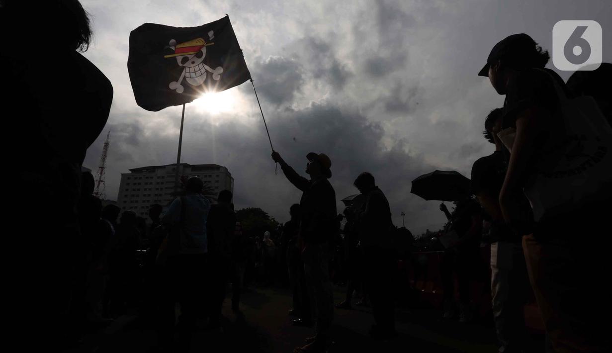 Dalam perjalanannya, 19 tahun Aksi Kamisan menjadi ruang ingatan kolektif bagi publik untuk menolak lupa atas kasus-kasus pelanggaran HAM berat masa lalu, seperti Tragedi Trisakti, Semanggi I & II, hingga pembunuhan aktivis Munir. Tampak dalam foto, peserta aksi Jaringan Solidaritas Korban untuk Keadilan mengibarkan bendera anime One Piece saat mengikuti peringatan 19 tahun Aksi Kamisan di Jalan Medan Merdeka Utara atau di seberang Istana Merdeka, Jakarta, 15 Januari 2026. (Liputan6.com/Helmi Fithriansyah)
