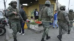 Tentara berpatroli di sekeliling penjara Inca selama keadaan darurat saat seorang penjual makanan berjualan di trotoar di Quito, Ekuador, Aetelah kaburnya seorang pemimpin geng yang berkuasa dari penjara, Selasa, 9 Januari 2024. (AP Photo/Dolores Ochoa)