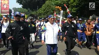 Menteri Komunikasi dan Informatika, Rudiantara (tengah) berlari membawa obor saat kirab obor Asian Games 2018 mengelilingi Kota Bogor, Jawa Barat, Selasa (14/8). Kota Bogor menjadi kota terakhir kegiatan pawai obor Asian Games. (Merdeka.com/Arie Basuki)