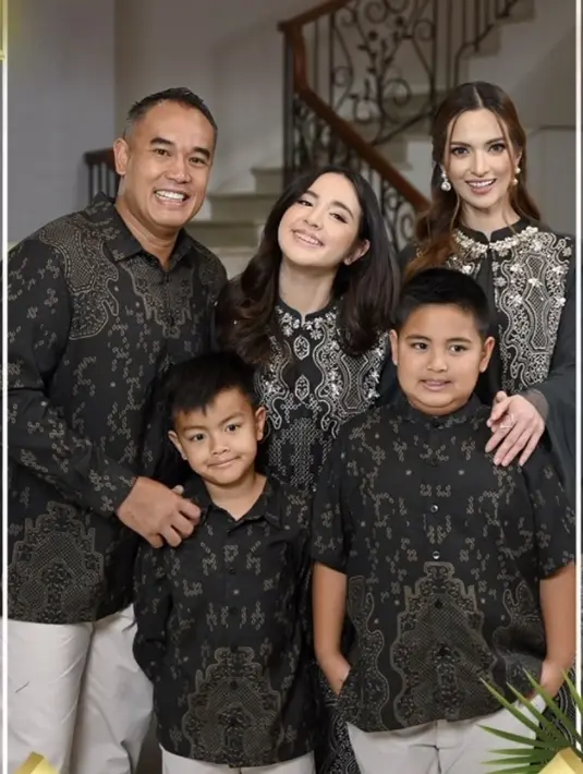 Nia Ramadhani dan keluarga mengenakan baju sarimbit warna hitam bermotif. Rambut coklat Nia diikat setengah bervolume dengan menyisakan poni depan yang membingkai wajah. [@geulis.id]