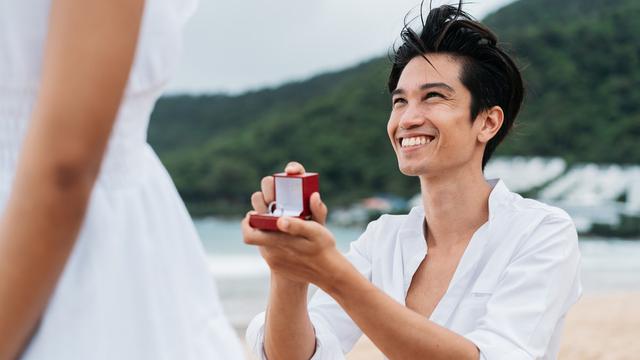 pria tersenyum membawa cincin