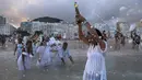 Penganut kepercayaan Afro-Brasil berdoa saat memberi penghormatan kepada Dewi Laut, Yemanja dalam tradisi upacara menjelang tahun baru di pantai Copacabana, Rio de Janeiro, Sabtu (29/12). Para jemaah berpakaian putih berkumpul di sini. (AP/Leo Correa)