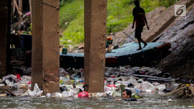 Petugas PPSU berenang untuk membersihkan tumpukan sampah yang tersangkut  di aliran anak kali Ciliwung, Jakarta, Senin (22/7/2019). Pembersihan sungai dari berbagai sampah tersebut dimaksudkan agar tidak ada penumpukan sampah dan sedimentasi saluran di sepanjang sungai. (Liputan6.com/Faizal Fanani)