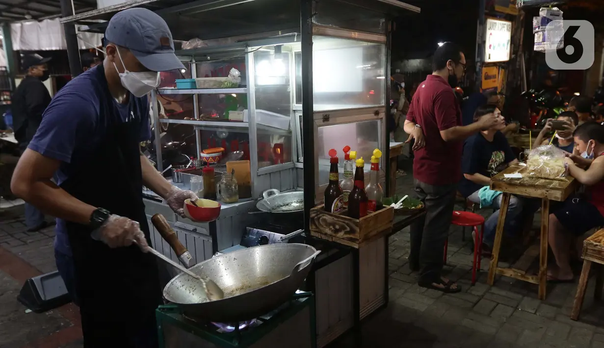 Mantan pegawai fungsional Biro Hukum KPK, Juliandi Tigor Simanjuntak memasak nasi goreng pesanan pelanggan di Jalan Raya Hankam, Bekasi, Rabu (13/10/2021). Sejumlah pegawai KPK yang dipecat kini beralih profesi. (Liputan6.com/Helmi Fithriansyah)