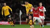 Striker Wolverhampton Wanderers Hwang Hee-chan (tengah) berebut bola dengan bek Arsenal Cedric Soares pada partai tunda pekan ke-20 Liga Inggris di Emirates Stadium, Jumat (25/2/2022) dini hari WIB. Arsenal menang dramatis 2-1 berkat dua gol di menit akhir. (Glyn KIRK / AFP)